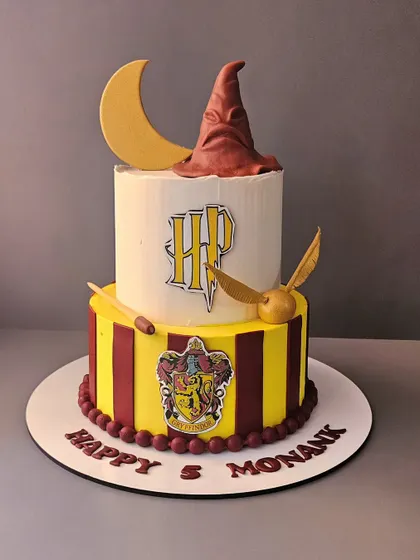 Step into the world of Harry Potter with this Gryffindor-themed cake. This two-tier vanilla and blueberry cake features the sorting hat, a golden snitch, and the house crest.