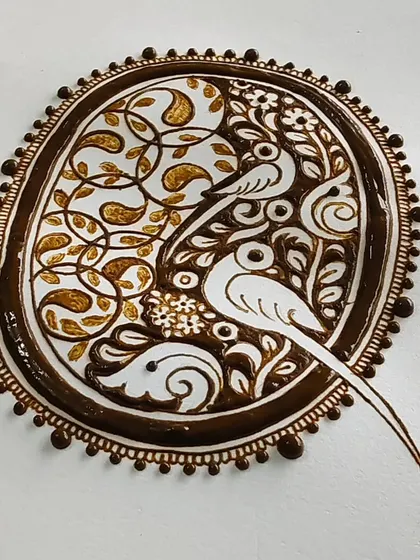The completed parrot cutwork design with the henna paste applied, showing the contrast and depth.
