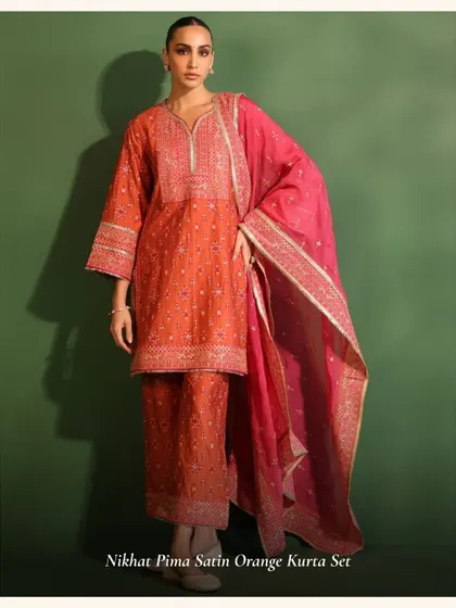 The Nikhat Pima Satin Orange Kurta Set is a bold and beautiful choice for the festive season.