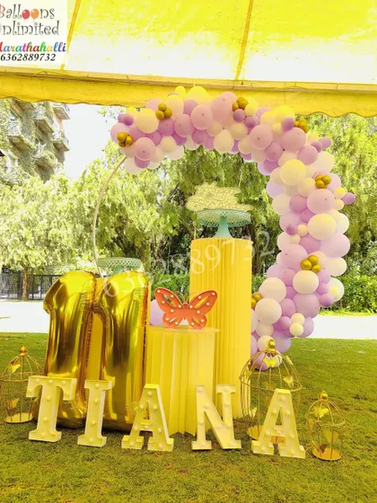 Celebrating a sunny 11th birthday outdoors with a pastel purple and yellow balloon arch, custom marquee letters, and elegant bird cage props.