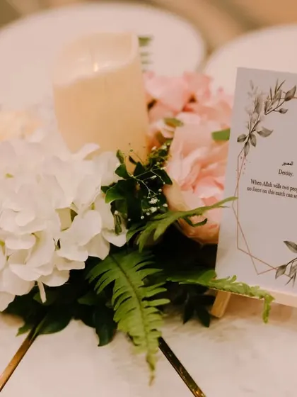 A charming centerpiece for a guest table, featuring a candle, a small floral arrangement, and a personalized card with a quote about love.