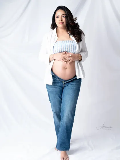 A beautiful and confident solo portrait. The mom-to-be looks radiant in this casual, modern outfit that proudly shows off her baby bump.