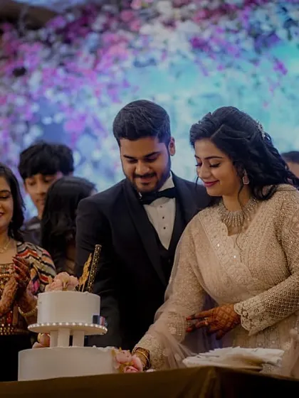 The couple cuts their beautiful two-tiered engagement cake together, surrounded by the applause and happy faces of their family.