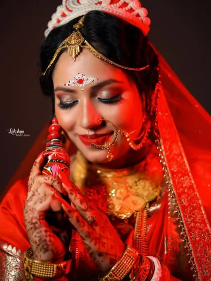 A serene portrait of the Bengali bride holding the sindoor box. Her closed eyes and gentle smile convey a sense of peace and happiness.