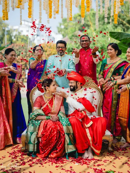 A wedding is not just about two people, but about two families coming together. Here, loved ones shower the couple with blessings and rose petals, creating a vibrant, joyful memory of a traditional Maharashtrian wedding ceremony.