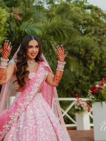 The bride, with her hands adorned with Mehendi, joyfully dancing during her entrance.