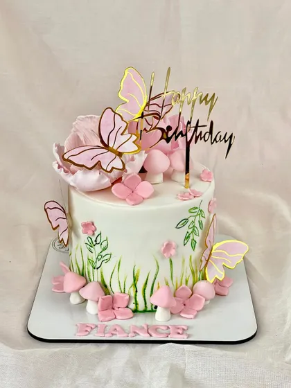 A lovely cake for a fiancée, featuring a hand-painted garden scene with pink flowers, mushrooms, and fluttering butterflies for a touch of enchantment.