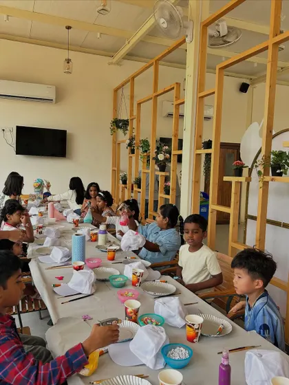 A candid shot of the art party in full swing. Kids are busy painting, chatting, and enjoying the creative process together in a bright, welcoming space.