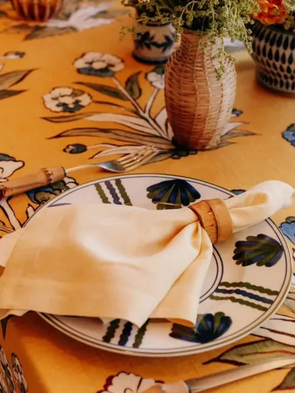 A close-up of a place setting that showcases attention to detail. The custom-printed plate, unique tablecloth, and bamboo-style cutlery all work together to enhance the event's theme.