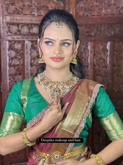 This portrait shows the bride's complete look, highlighting the harmony between her makeup, jewelry, and vibrant green and maroon saree.