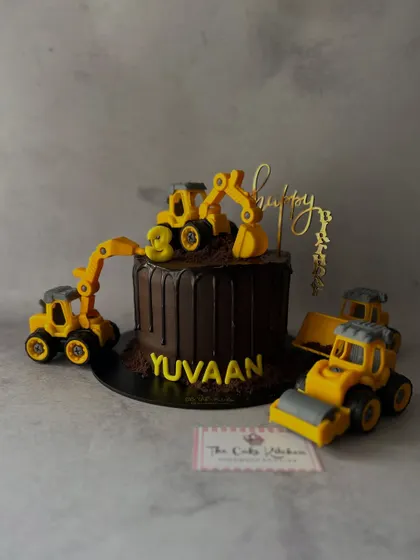 For a little one who loves trucks, this construction-themed cake features a chocolate drip base and is surrounded by toy excavators and bulldozers.