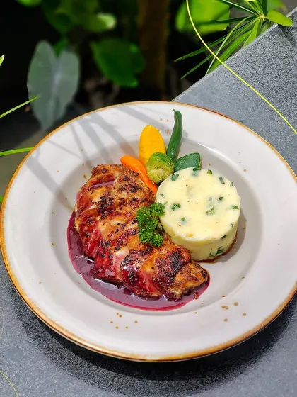 A hearty plate of grilled chicken served with mashed potatoes and steamed vegetables. It's comfort food, elevated.