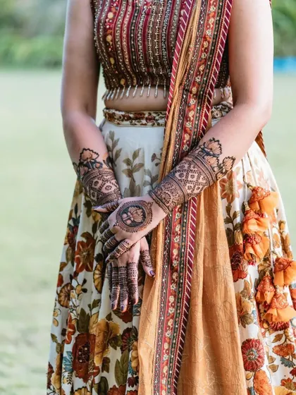 The client's mehndi, featuring modern lotus mandalas, perfectly complements her beautiful, earthy-toned lehenga.