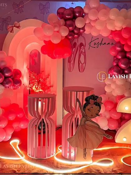 A graceful ballerina-themed party in shades of pink and red, featuring a large cutout of a dancer, a light-up number '2', and elegant decor elements.
