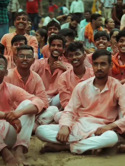 A candid shot of a group of young devotees resting on the beach during the visarjan. Their smiles and camaraderie capture the joyful and communal spirit of the festival.