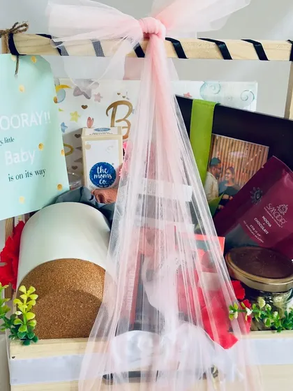 Welcoming a new life is a joyous occasion, and this baby shower hamper is designed to match. Packed in a beautiful pinewood basket, it includes essentials from The Moms Co., a personalized photo frame, and sweet treats for the parents-to-be.