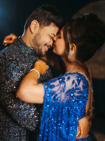A sweet moment between Shree and Abhishek. His navy blue Manish Malhotra ensemble perfectly complements her royal blue gown, showcasing a coordinated couple look.