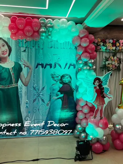 A fairy-themed birthday party with a personalized photo backdrop. The decor includes fairy cutouts, balloon columns, and foil number balloons for the age.
