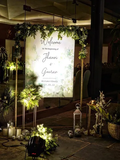 A personalized welcome sign for the couple, beautifully illuminated and surrounded by lush greenery, lanterns, and candles. This creates a stunning first impression for guests as they arrive.