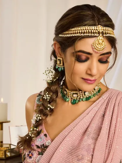 A bohemian-inspired bridal braid. This loose, textured braid is woven with baby's breath and paired with a sheeshpatti for a look that is perfect for a Mehendi or a relaxed outdoor wedding.