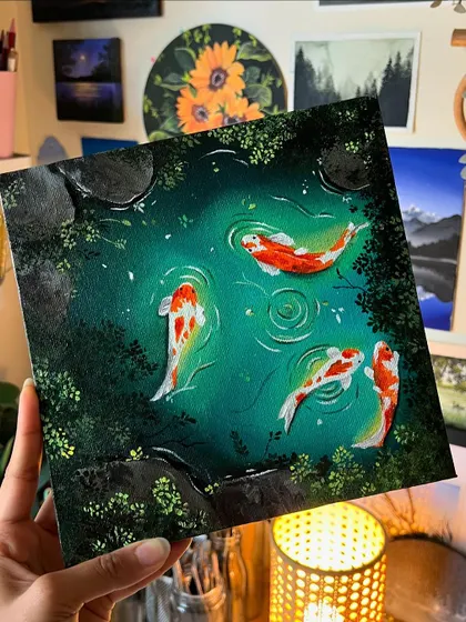Holding up my finished koi pond painting. The deep greens and the bright fish create a beautiful contrast, and the lighting in my studio really makes the colors glow.