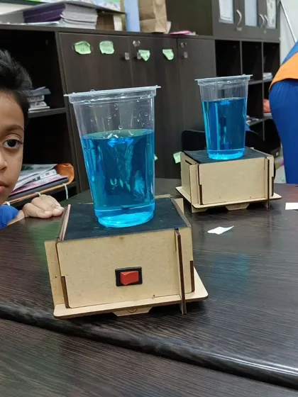 A student observes the vortex created in a cup of water on a vibrating platform he built. This experiment is a great visual demonstration of physics principles.
