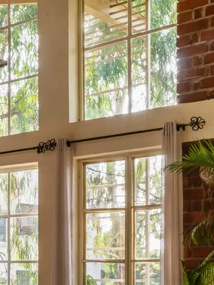 The combination of exposed brick, large windows, and indoor plants creates a space that feels both expansive and intimate.