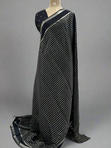 A mannequin draped in a classic black saree with silver stripes.