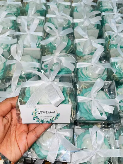 A full view of the mint green and white peony candle favors, each packaged in a clear box with a custom tag.