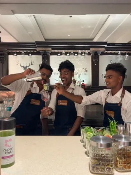 The moment of truth. A student carefully pours a freshly shaken cocktail while his teammates watch with excitement. It's all about learning by doing.