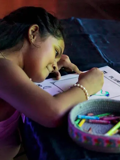 A child carefully coloring her picture, excited to see it get scanned and animated on the big screen.