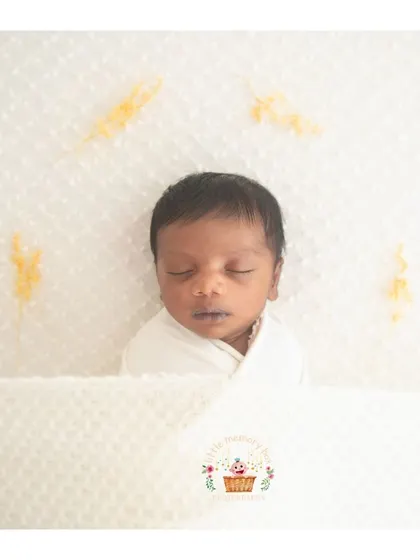 A simple, clean, and minimalist newborn portrait. Wrapped snugly in white on a white background, all the focus is on the baby's peaceful, sleeping face.
