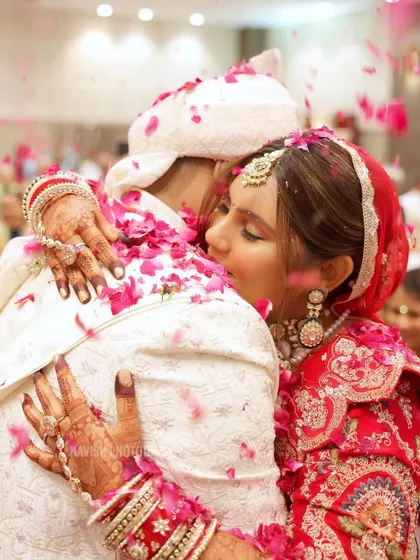 A close-up of an emotional hug between the bride and groom, with flower petals showering down on them.