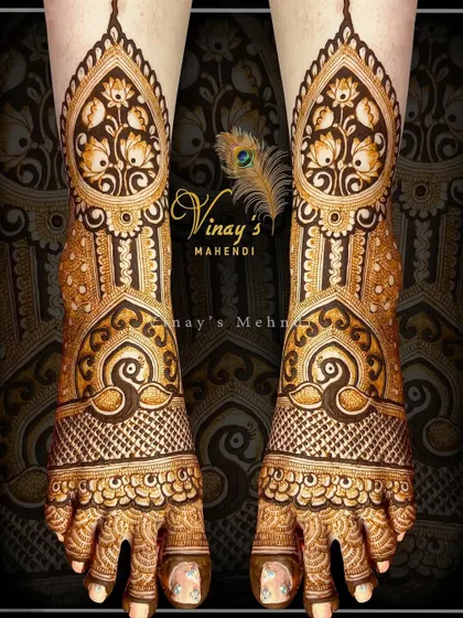 A stunning bridal feet design with large lotus motifs on the top of the feet and peacocks near the ankles, creating a rich and layered look.