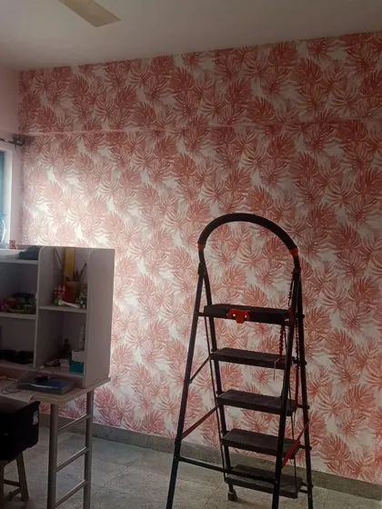 A study or kids' room with a bright orange leaf pattern wallpaper. The color is cheerful and stimulating, great for a creative environment.