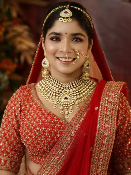 A classic bridal portrait. The traditional red lehenga and jewelry are perfectly complemented by the soft, glowing makeup.