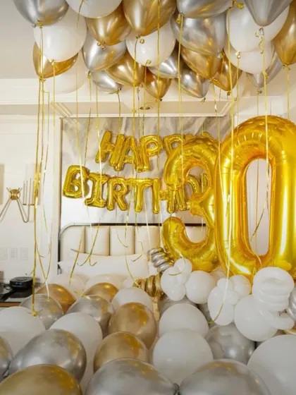 A closer look at the lavish bedroom decor, with balloons filling the bed and floating to the ceiling.