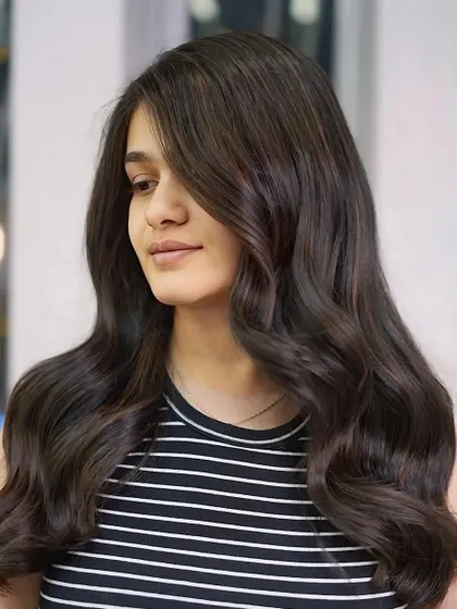 A side view of the long, wavy brunette style, showcasing the beautiful color blend and healthy, flowing locks.
