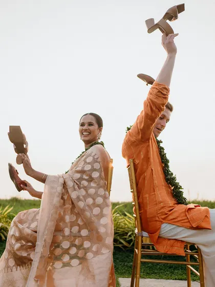 A couple plays a fun wedding game outdoors with the beautiful Kerala landscape as their backdrop.
