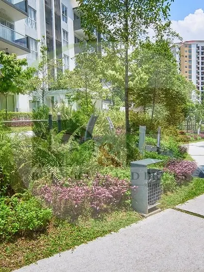 A lush, green walkway in a residential community. This landscape features dense, layered plantings with a variety of textures and colors, creating a natural and immersive environment for residents.