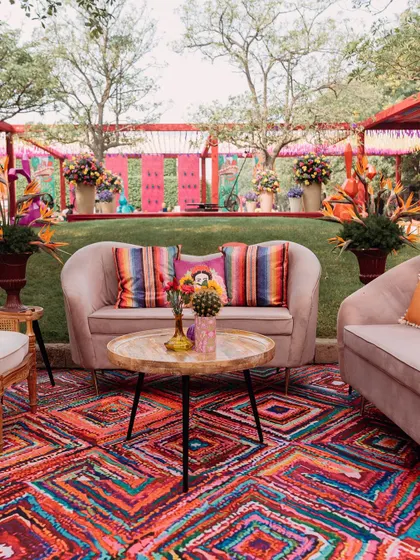 A comfortable lounge setting at our Mexican fiesta event. The vibrant, multi-colored rug provides a bold foundation for the neutral-toned sofas, which are accented with colorful striped and Frida Kahlo-themed cushions.