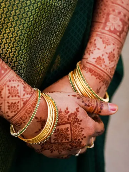 A close-up of a mature henna stain with simple gold bangles. This shows how beautifully henna can accessorize a look, even with simpler designs.