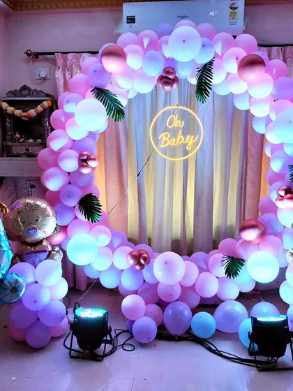 A lovely balloon ring backdrop for a baby shower in shades of purple and pink. The "Oh Baby" neon sign, along with foil balloons shaped like a baby carriage and bottle, makes the theme clear and cute.