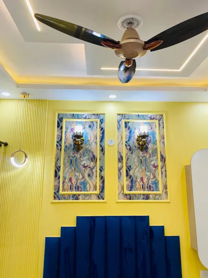 A close-up of the feature wall in the master bedroom. The combination of yellow walls, a blue velvet headboard, and traditional sconce lights is striking.