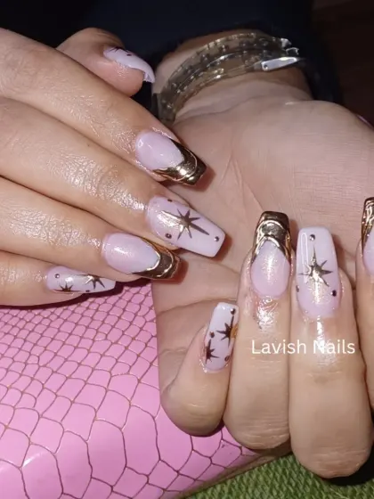 A modern French manicure with a metallic gold tip and delicate star details.
