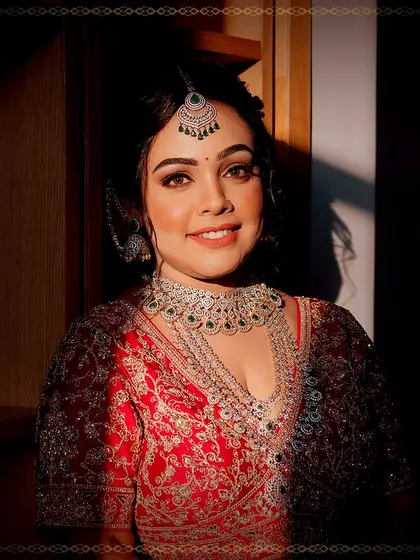 A beautiful sunkissed portrait of the bride. The golden light highlights her flawless makeup and the rich details of her red bridal lehenga and diamond jewellery.