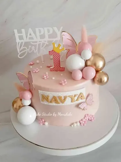 A pretty first birthday cake for Navya. The soft pink design is decorated with butterflies, balloons, and a little crown for the birthday princess.