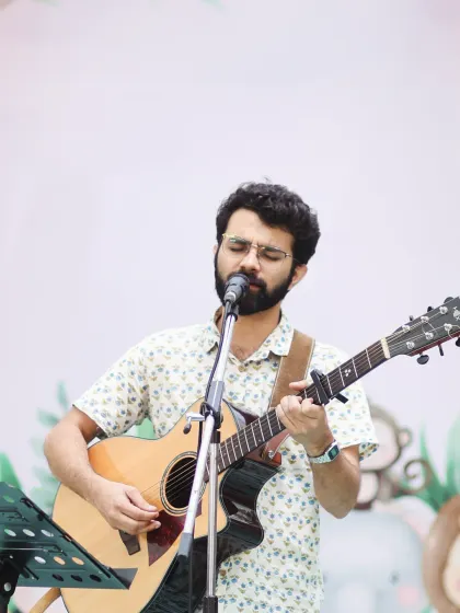 Our founding vocalist sings with acoustic guitar in the performance portrait we shared for his birthday.