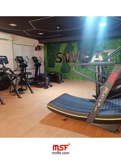 The cardio zone at a "SWEAT" branded gym, featuring our Curve Treadmill, ellipticals, and recumbent bikes.