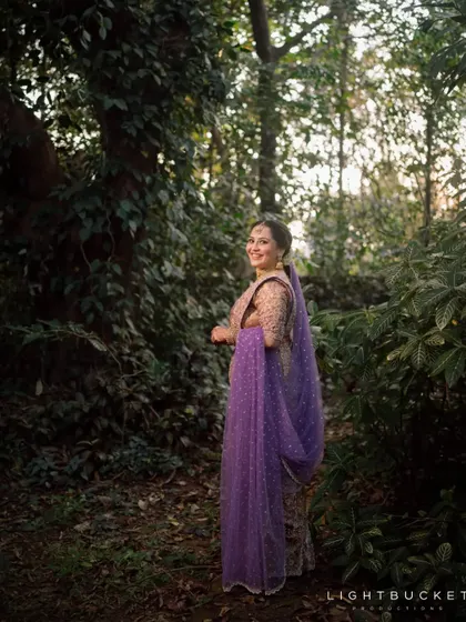 The bride in a serene forest-like setting, her purple veil adding a touch of magic to the shot.